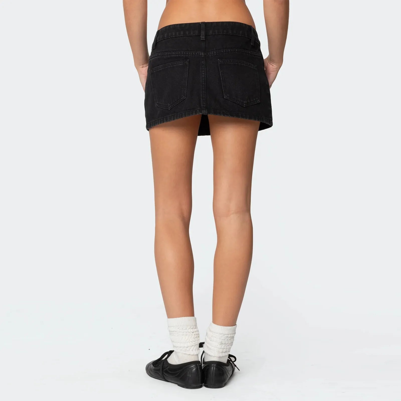 Femme portant une jupe courte jean scandinave noire vue de dos avec chaussettes blanches et chaussures noires