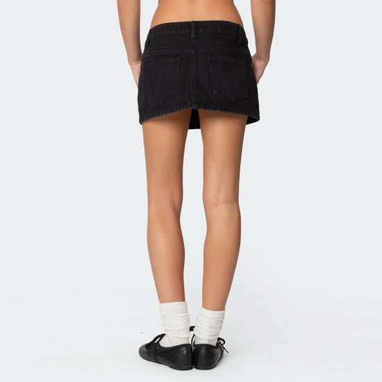 Femme portant une jupe courte jean scandinave noire vue de dos avec chaussettes blanches et chaussures noires