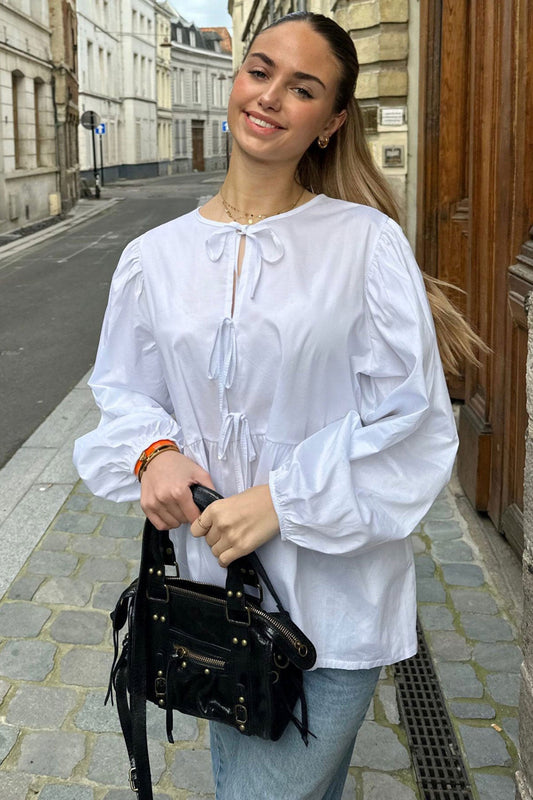 Haut scandinave femme tendance blanc à manches bouffantes porté avec un sac noir élégant