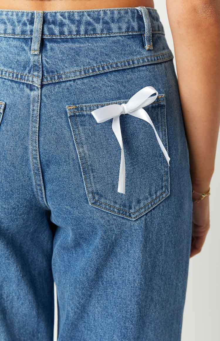 Jean style stockholm tendance en denim bleu avec un nœud blanc décoratif sur la poche arrière