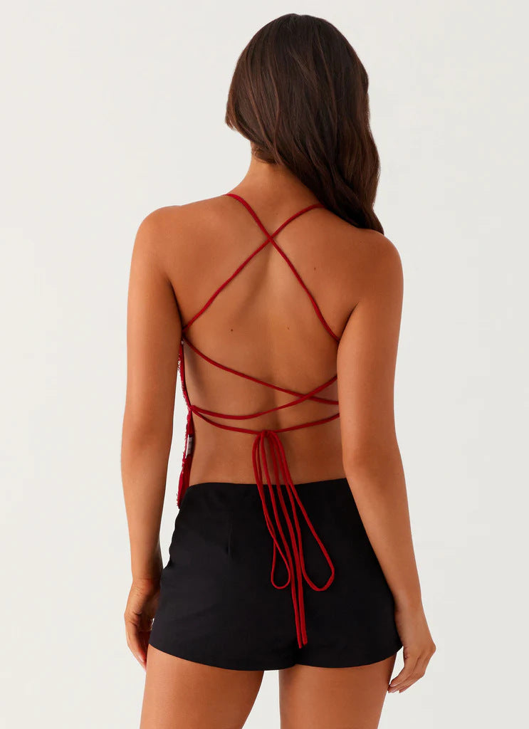 Femme portant un haut bleu style ibiza avec dos nu et lanières croisées et une jupe noire