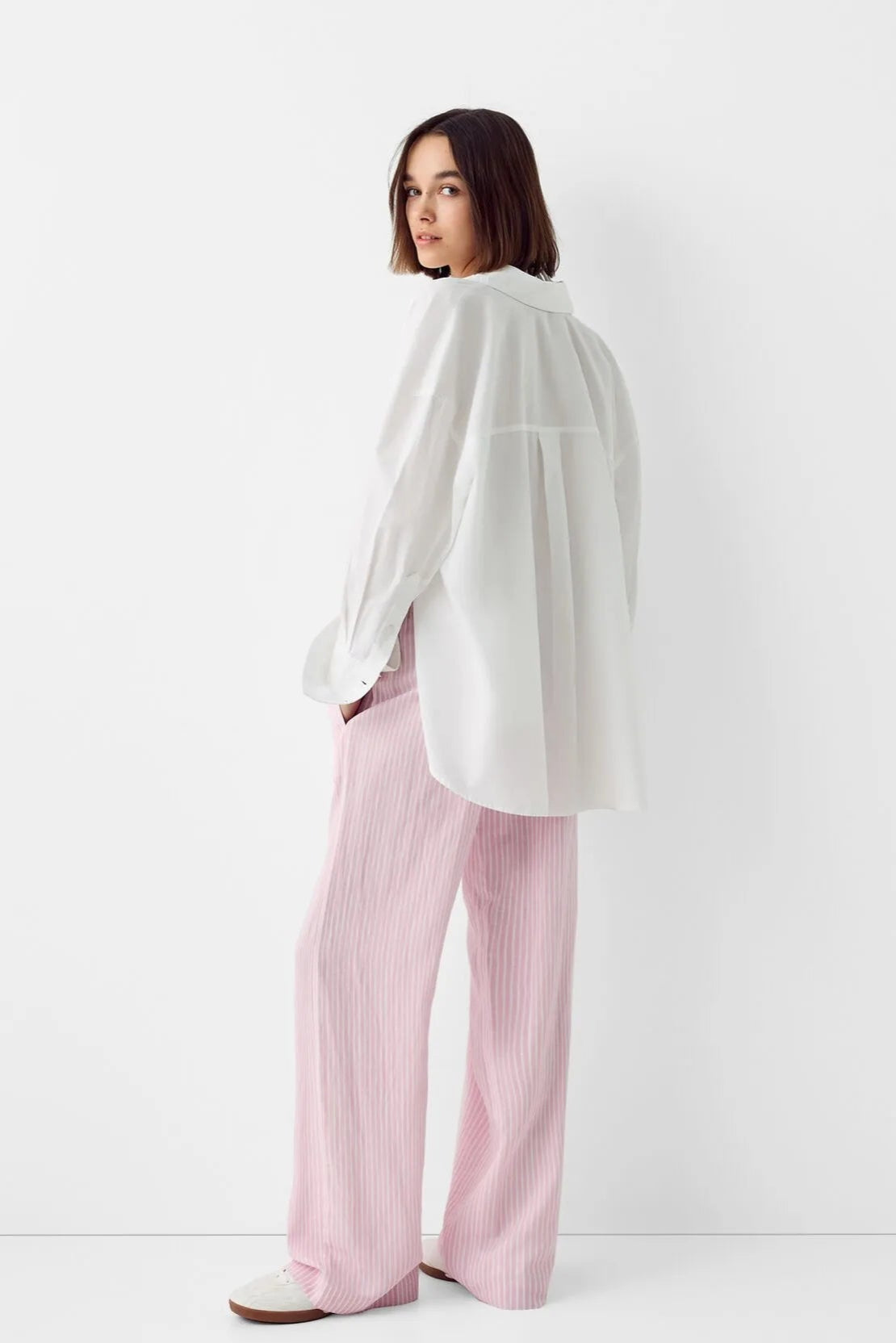 Femme portant un pantalon scandinave style clean girl stockholm style rose avec un haut blanc fluide