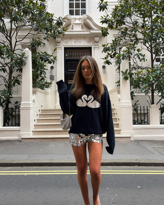 Femme portant un pull coton femme scandinave bleu marine avec motif cygnes blancs en ville