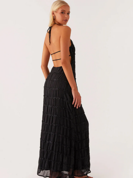Femme portant une robe élégante soirée jaune noire longue dos nu avec détails en tissu texturé