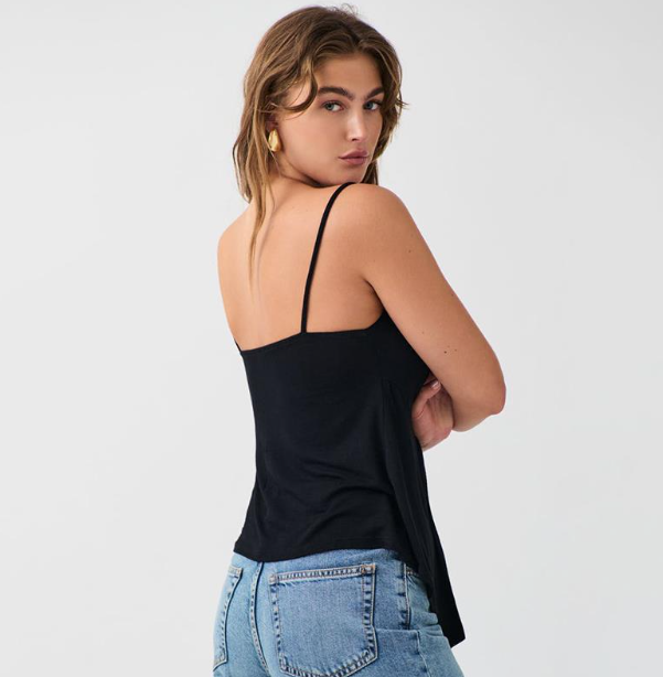 Top noir tendance femme à fines bretelles porté par une femme de dos avec un jean bleu