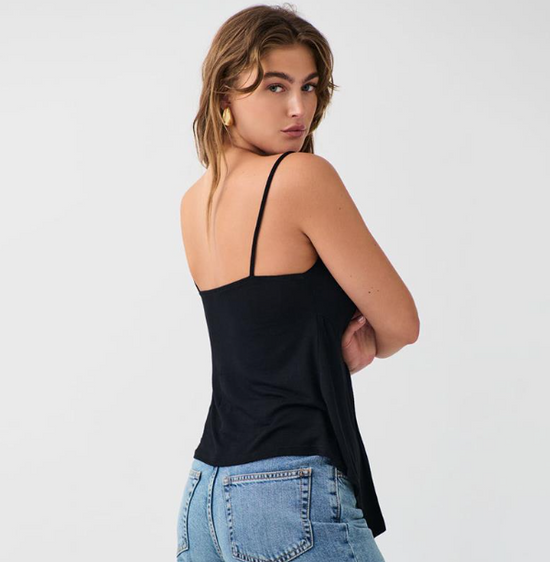Top noir tendance femme à fines bretelles porté par une femme de dos avec un jean bleu