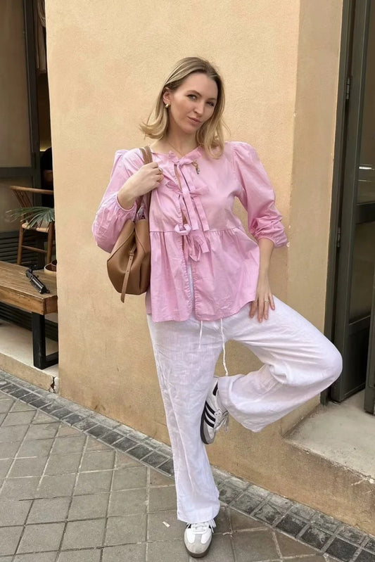 Femme portant un top blanc clean girl tendance avec pantalon blanc et sac à main marron