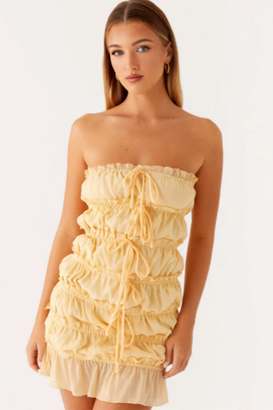 Femme portant une robe courte soirée vanillagirl jaune à volants sans bretelles élégante