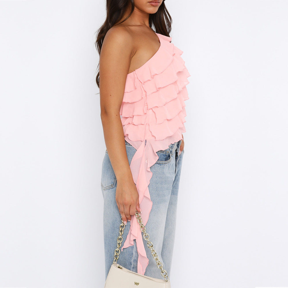 Top rose robe soirée chic à volants asymétriques porté avec un jean clair et sac à main beige